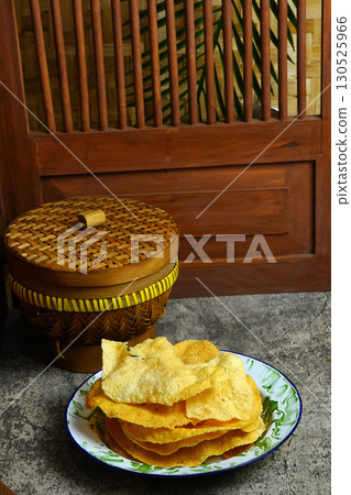 Golden and crispy opak or Indonesian Cassava Crackers on a vintage enamel plate. A popular savory snack with a crunchy texture. Golden and crispy opak or Indonesian Cassava Crackers on a vintage enamel plate. A popular savory snack with a crunchy texture. 130525966