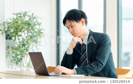 A male businessman worried while using a computer A male businessman worried while using a computer 130526014