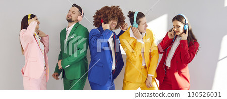 Young happy people listening to music in headphones wearing bright suits on gray background. 130526031