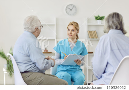 A doctor listens to an elderly couple sitting opposite, close-up 130526032