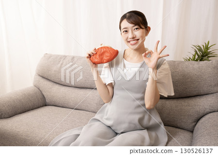 An eight-month pregnant woman sitting on a sofa and holding a red wallet An eight-month pregnant woman sitting on a sofa and holding a red wallet 130526137