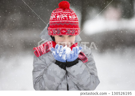 Happy boy holding snow in his hand. The child rejoices in winter and the first snow. Happy boy holding snow in his hand. The child rejoices in winter and the first snow. 130526195