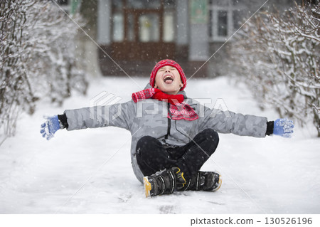 Happy boy catches snowflakes with his mouth. The child rejoices in winter and the first snow. Happy boy catches snowflakes with his mouth. The child rejoices in winter and the first snow. 130526196