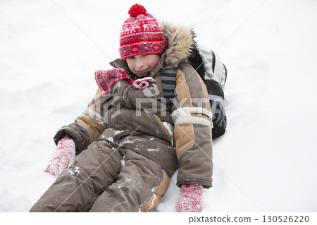 Funny boy in winter goes to school with a backpack.A little boy with a schoolbag sits in a snowdrift. 130526220