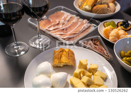 Appetizer table with red wine, mozzarella, hard cheese, prosciutto, anchovies, bread, olives Appetizer table with red wine, mozzarella, hard cheese, prosciutto, anchovies, bread, olives 130526262