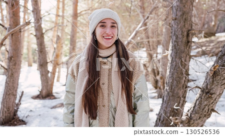 Young woman smiling in snowy forest wearing winter clothes 130526536