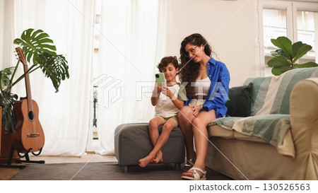 Mother and son using smartphone at home, enjoying quality time together 130526563