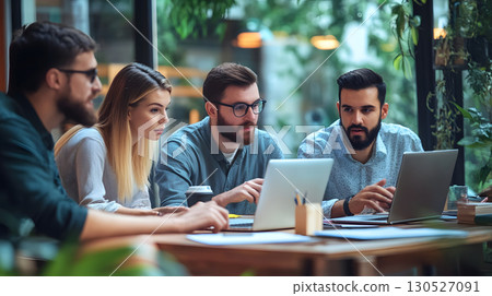 Group of professionals working together in an office, collaborating around a laptop during a team meeting. Great for teamwork, startup, and corporate use. 130527091