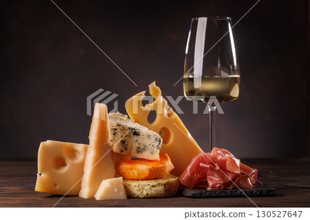 Assorted cheeses paired with glass of wine on a rustic table Assorted cheeses paired with glass of wine on a rustic table 130527647