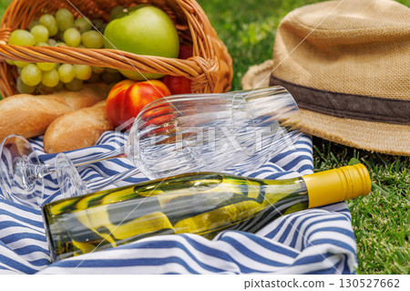 Picnic with wine, fruits, and baguette on a green meadow Picnic with wine, fruits, and baguette on a green meadow 130527662
