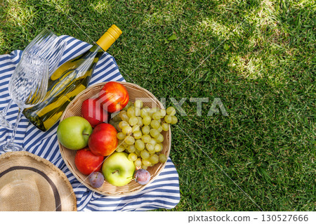 Picnic with wine, fruits, and baguette on a green meadow Picnic with wine, fruits, and baguette on a green meadow 130527666