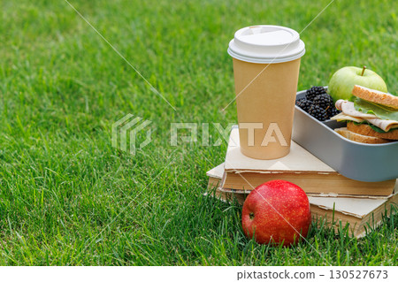Picnic on a lawn with books, sandwiches, fruits, and coffee Picnic on a lawn with books, sandwiches, fruits, and coffee 130527673