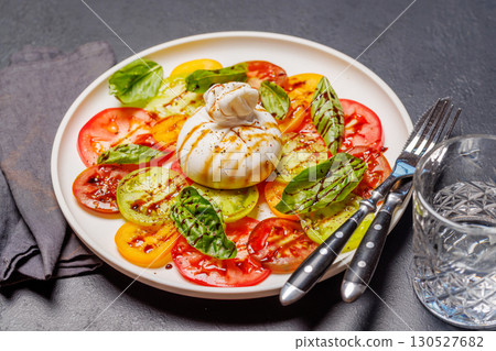 Fresh burrata served on slices of colorful tomatoes Fresh burrata served on slices of colorful tomatoes 130527682