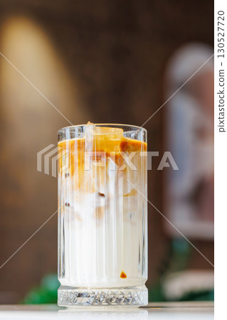 Iced latte in a clear glass with visible coffee and milk layers 130527720