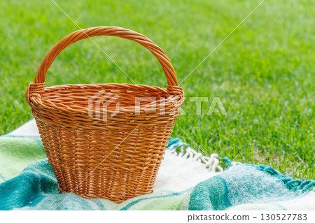 Picnic basket on a green lawn under sunny skies, ready for an outdoor meal 130527783