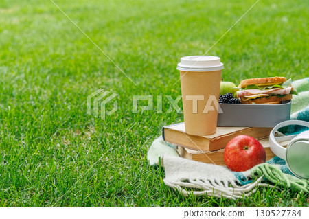 Romantic picnic on a lawn with books, fresh sandwiches, fruits, and coffee 130527784