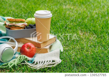 Romantic picnic on a lawn with books, fresh sandwiches, fruits, and coffee Romantic picnic on a lawn with books, fresh sandwiches, fruits, and coffee 130527785