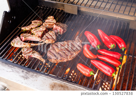 Juicy steaks and bell peppers sizzling on a grill Juicy steaks and bell peppers sizzling on a grill 130527838