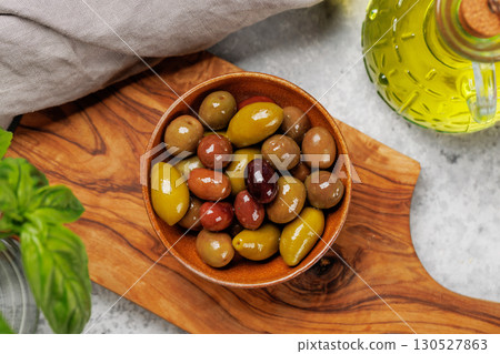 An assortment of various olives presented in a bowl, showcasing different colors, textures, and flavors 130527863