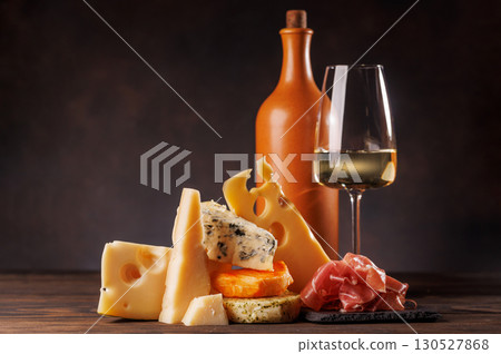 Assorted cheeses paired with glass of wine on a rustic table 130527868