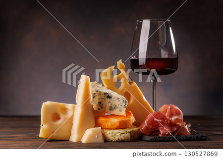 Assorted cheeses paired with glass of wine on a rustic table Assorted cheeses paired with glass of wine on a rustic table 130527869