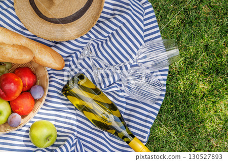 Picnic with wine, fruits, and baguette on a green meadow 130527893
