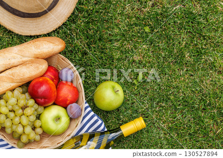 Picnic with wine, fruits, and baguette on a green meadow 130527894