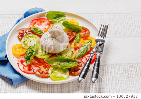 Fresh burrata served on slices of colorful tomatoes 130527918