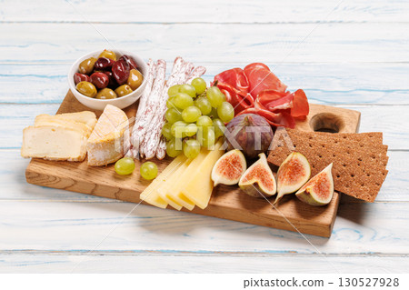 Antipasto platter with prosciutto, cheese, olives, salami, figs, grapes, and crackers 130527928