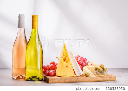A delectable arrangement of various cheeses, fresh grapes, and wine 130527950