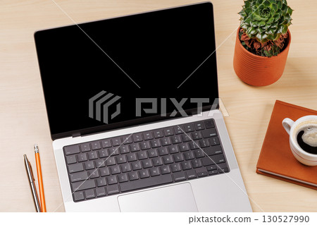 A clean and minimal desk setup featuring a laptop and a coffee cup 130527990