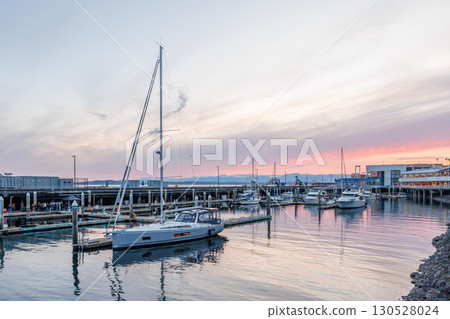 Seattle harbor during sunset with calm water, and silhouettes of boats 130528024