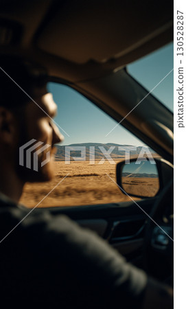 Driver enjoying road trip across arid plains, traveling towards distant mountains on sunny day 130528287