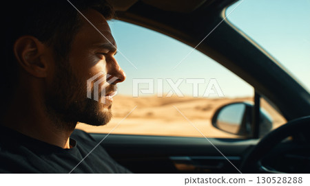 Young man driving a modern car through a desert landscape, enjoying the journey and the scenic view 130528288