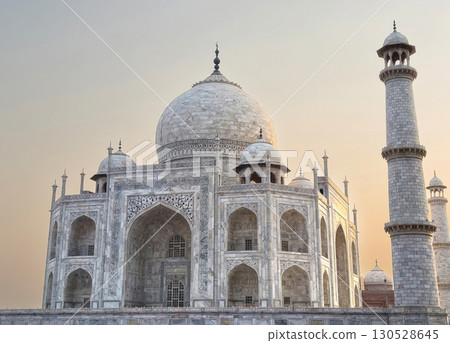 Taj Mahal in Agra, India. Majestic white marble mausoleum with domes, ornate carvings in golden hour Taj Mahal in Agra, India. Majestic white marble mausoleum with domes, ornate carvings in golden hour 130528645