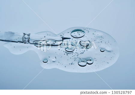 Transparent serum with bubbles and dropper dropper on a blue background. 130528797