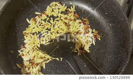 Cooking delicious orzo in a frying pan, close-up. 130528999