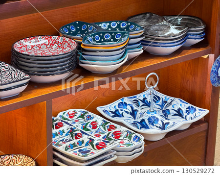 Ceramic plates with floral and geometric patterns arranged on wooden shelves. Cultural craftsmanship, decorative utility, and artisan heritage in daily life. 130529272