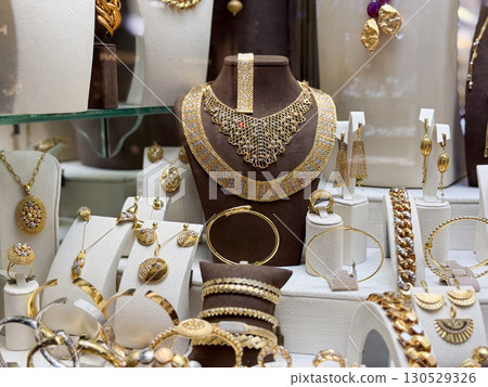 Golden necklace and earrings in a jewelry store. Luxury, wealth, and decorative fashion accessories. Golden necklace and earrings in a jewelry store. Luxury, wealth, and decorative fashion accessories. 130529326