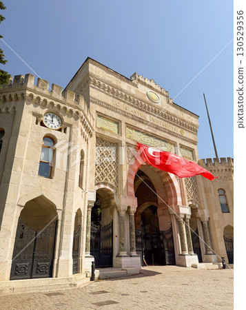 Historic entrance gate of Istanbul University with Turkish flag hanging. Architecture, culture, and heritage representing education, tradition, and national identity. Historic entrance gate of Istanbul University with Turkish flag hanging. Architecture, culture, and heritage representing education, tradition, and national identity. 130529356