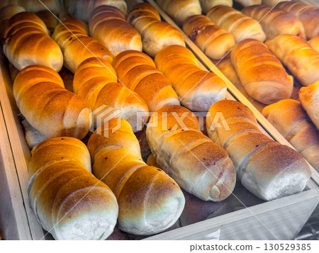 Fresh baked bread rolls arranged on bakery tray with golden crust surface. Food, gastronomy, and retail product representing tradition, nutrition, and culinary lifestyle. 130529385