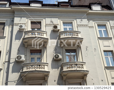 Historic facade with balconies and decorative architectural ornaments in urban environment. Residential housing and cultural tradition reflecting lifestyle, heritage, and city neighborhood design. 130529425