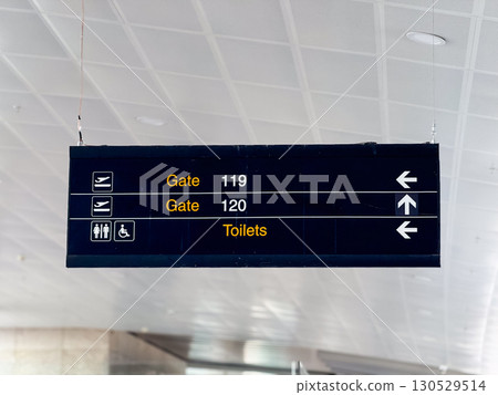 Airport directional sign with gates information in terminal hall. Travel navigation, passenger guidance, and public facility signage for aviation infrastructure. Airport directional sign with gates information in terminal hall. Travel navigation, passenger guidance, and public facility signage for aviation infrastructure. 130529514