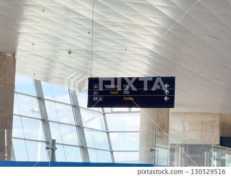 Airport directional sign with gates information in terminal hall. Travel navigation, passenger guidance, and public facility signage for aviation infrastructure. 130529516