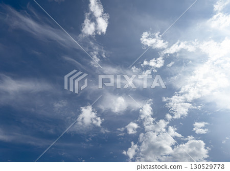 dynamic sky scene featuring wispy cirrus streaks and fluffy cumulus clouds scattered across a deep 130529778