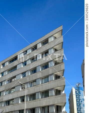 Modern urban apartment building with a sharp angular corner against a clear blue sky. The structure Modern urban apartment building with a sharp angular corner against a clear blue sky. The structure 130529820