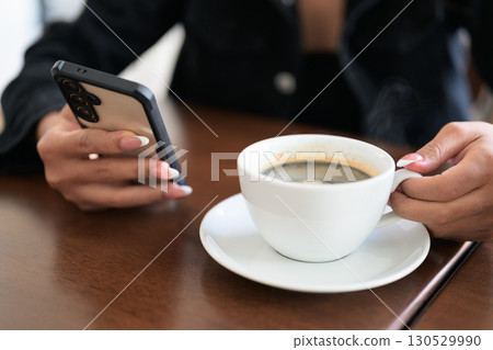 Close-up of woman hands texting and chatting using mobile phone indoors in coffee shop restaurant 130529990