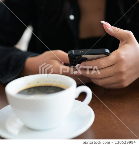 Close-up of woman hands texting and chatting using mobile phone indoors in coffee shop restaurant Close-up of woman hands texting and chatting using mobile phone indoors in coffee shop restaurant 130529994