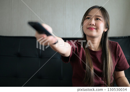 Thai woman sitting on sofa watching television at home Thai woman sitting on sofa watching television at home 130530034