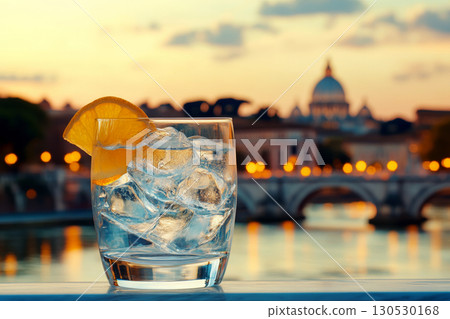 A glass of iced drink with a lemon slice sits on a table with a blurred cityscape in the background. Concept of refreshment and urban atmosphere. For travel photo. A glass of iced drink with a lemon slice sits on a table with a blurred cityscape in the background. Concept of refreshment and urban atmosphere. For travel photo. 130530168